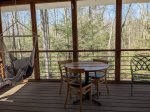 The screened in back porch with table, chairs and chair hammock